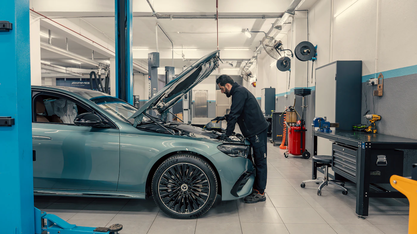 A mechanic working on a car engine in a repair workshop.