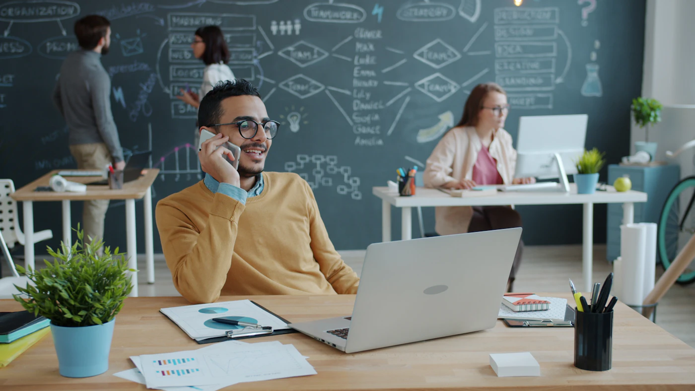 A business owner speaking on a phone in an open office.