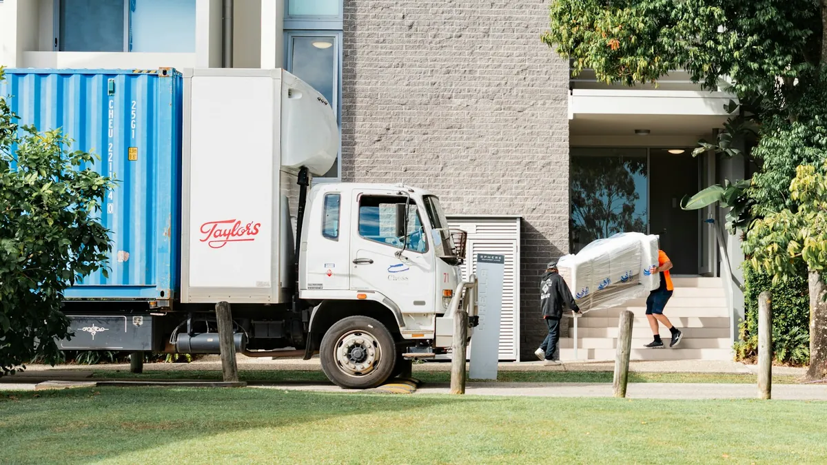 Moving crew and truck carrying household furniture outside an apartment building