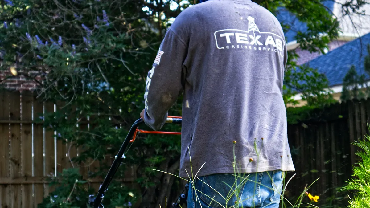 Lawn care worker mowing a residential yard during a landscaping service