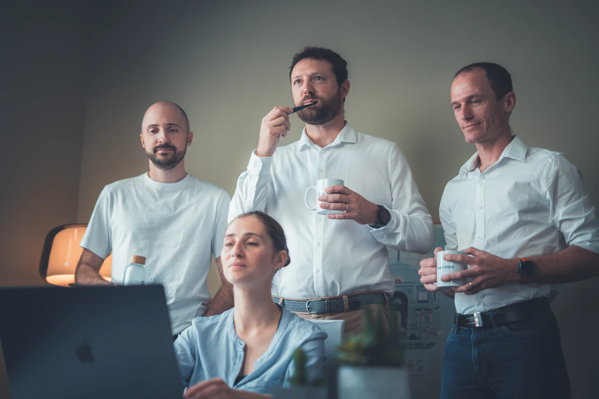 Four people reviewing a laptop together during a meeting.