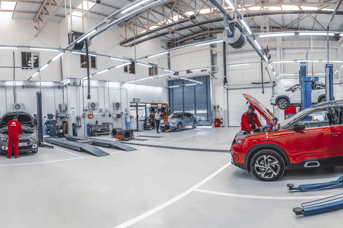 Vehicles and service lifts inside a bright automotive repair workshop.